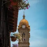 Golden clock tower with potted flowers in Socorro, Santander, Colombia.