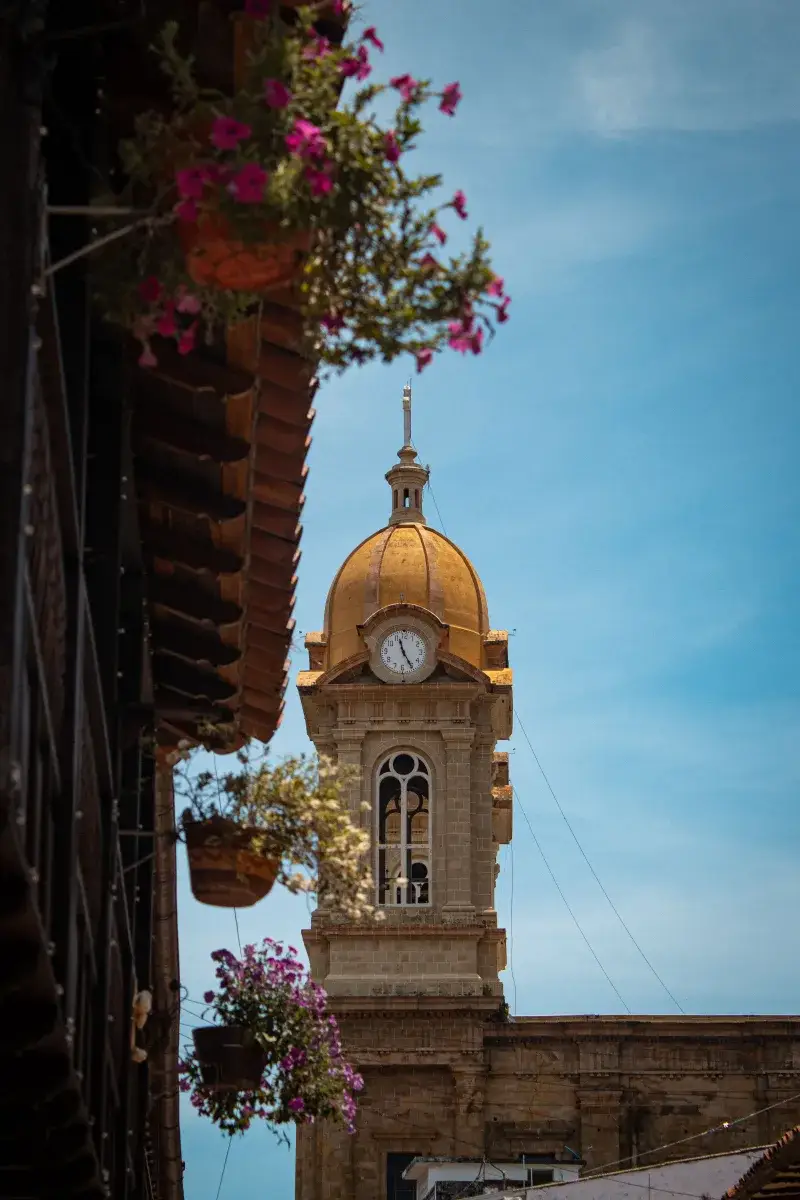 Golden clock tower with potted flowers in Socorro, Santander, Colombia.