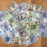 Aerial view of mixed Euro and US Dollar banknotes on a wooden floor, symbolizing global finance.