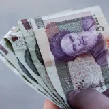 Detailed view of Iranian rial banknotes held in hand, illustrating finance and economy in Iran.