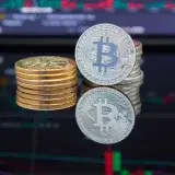 Bitcoin coins stacked in front of cryptocurrency trading chart reflecting market trends.