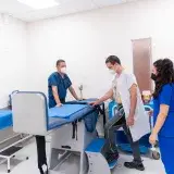Patient undergoing medical examination assisted by healthcare professionals in a clinic.