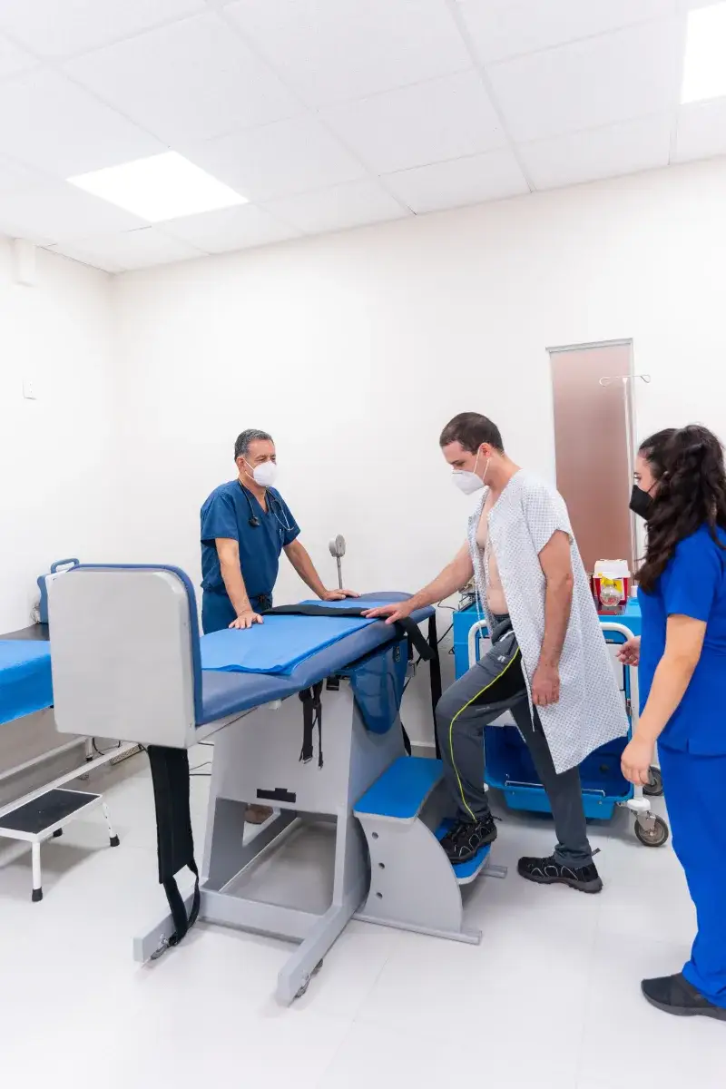 Patient undergoing medical examination assisted by healthcare professionals in a clinic.