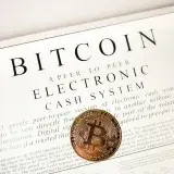 Bitcoin cryptocurrency coin on top of its white paper. Digital currency concept.