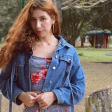 Young woman with red hair posing in a denim jacket outdoors in Táchira, Venezuela.