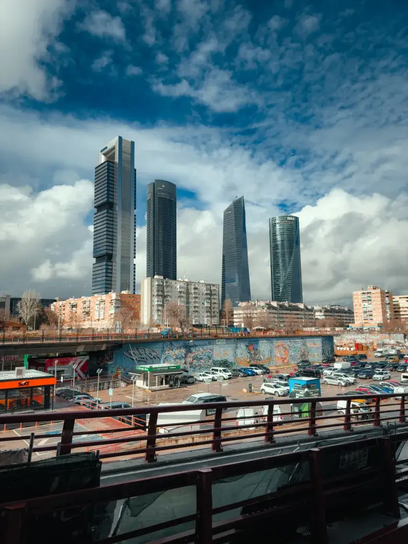 Dynamic view of the Cuatro Torres skyscraper complex under a dramatic sky in Madrid, Spain.