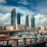 Dynamic view of the Cuatro Torres skyscraper complex under a dramatic sky in Madrid, Spain.