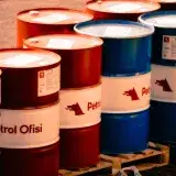 A collection of red and blue oil barrels labeled 'Petrol Ofisi' in an outdoor industrial setting in Turkey.
