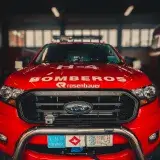 Front view of a red fire truck with 'Bomberos' displayed, parked indoors.