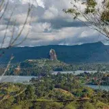 Breathtaking aerial view of El Peñol and lush landscape in Colombia, surrounded by lakes under dramatic skies.