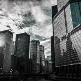 Chicago cityscape featuring Trump Tower with dramatic reflections against a cloudy sky.