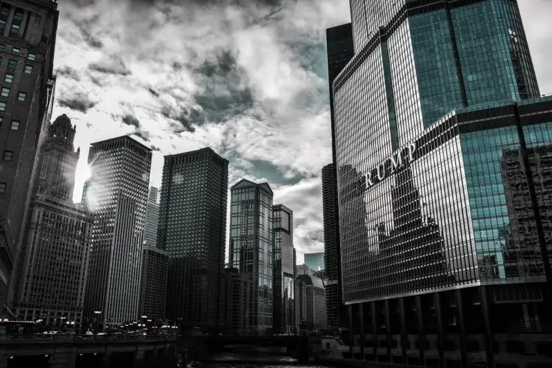 Chicago cityscape featuring Trump Tower with dramatic reflections against a cloudy sky.