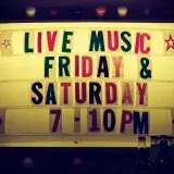 Illuminated vintage marquee promoting live music nights on Friday and Saturday.