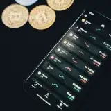 From above of modern smartphone with financial data on screen placed on black table near scattered coins