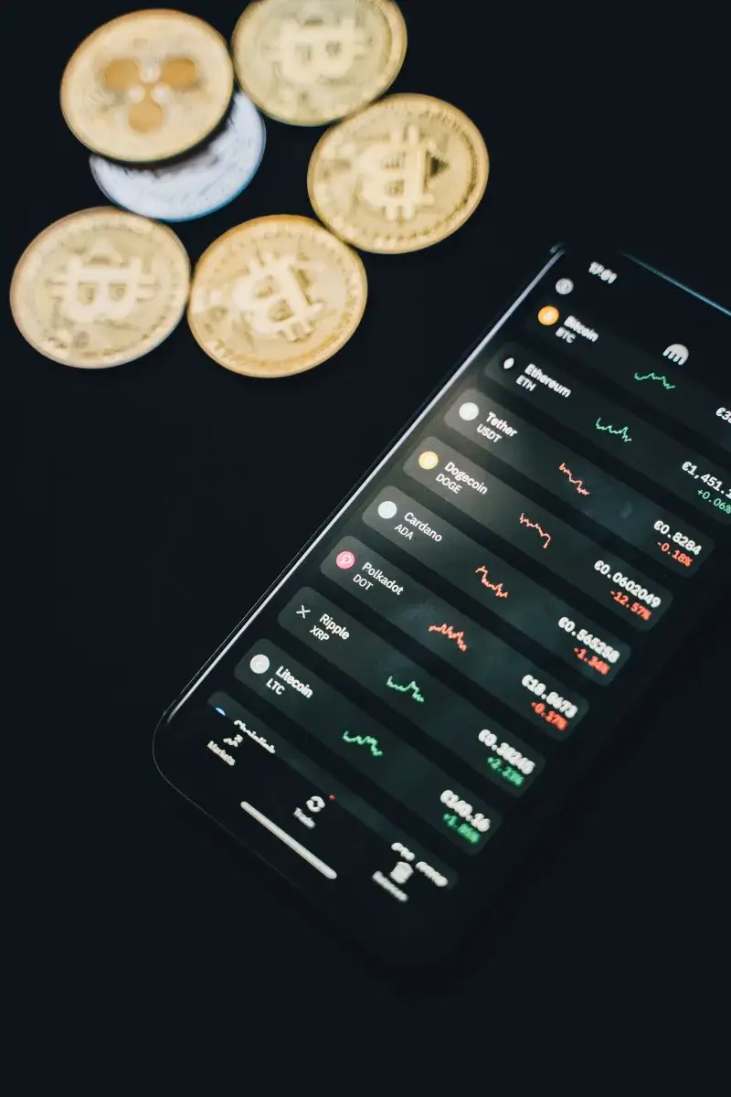 From above of modern smartphone with financial data on screen placed on black table near scattered coins