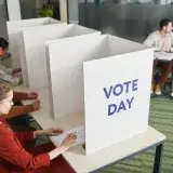 People casting votes in a polling station on election day, emphasizing civic engagement.