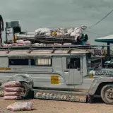 Man stands atop a packed jeepney with cargo