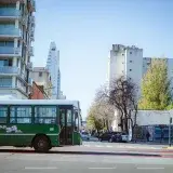 A green public bus traveling on a city street in Buenos Aires, Argentina, showcasing urban life.