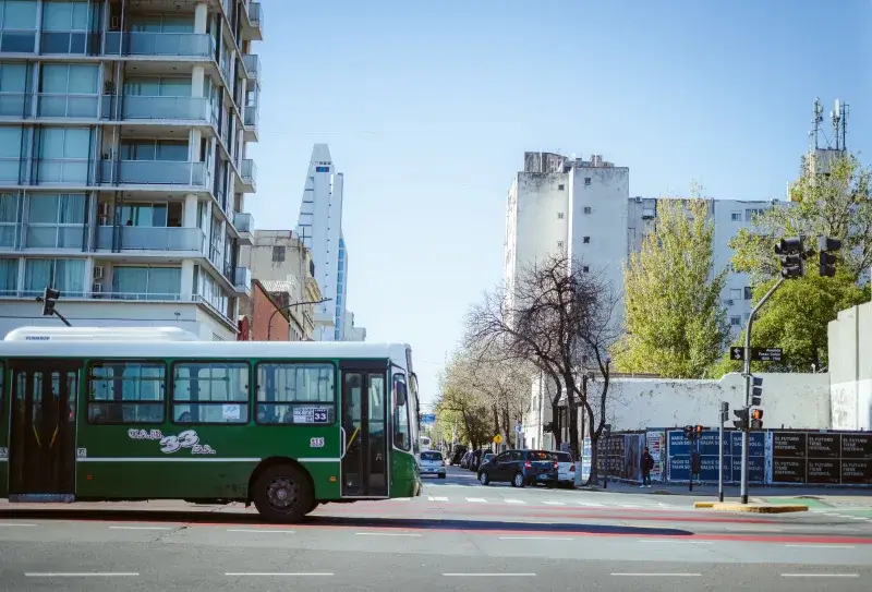 A green public bus traveling on a city street in Buenos Aires, Argentina, showcasing urban life.