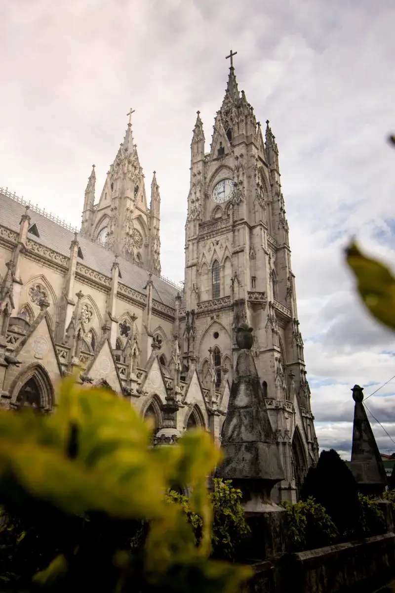 Stunning view of the iconic Gothic Basilica del Voto Nacional in Quito, Ecuador with cloudy sky.