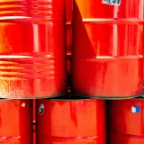 Bright red industrial oil barrels stacked outdoors in daylight, showcasing vivid color and industrial theme.
