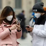 Una pareja con mascarillas revisa sus teléfonos móviles cerca de la Pirámide del Louvre, en París, Francia.