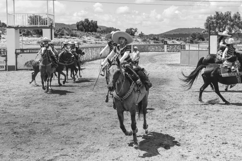 Traditional Mexican charros riding horses in a rural rodeo arena, San Juan Tizahuapan.