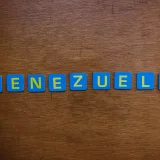 Blue and yellow letter tiles spelling Venezuela on a wooden surface.