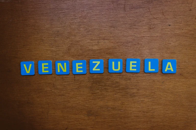 Blue and yellow letter tiles spelling Venezuela on a wooden surface.