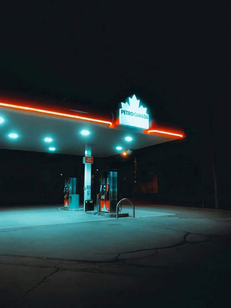 A neon-lit Petro Canada gas station illuminated against the night sky.