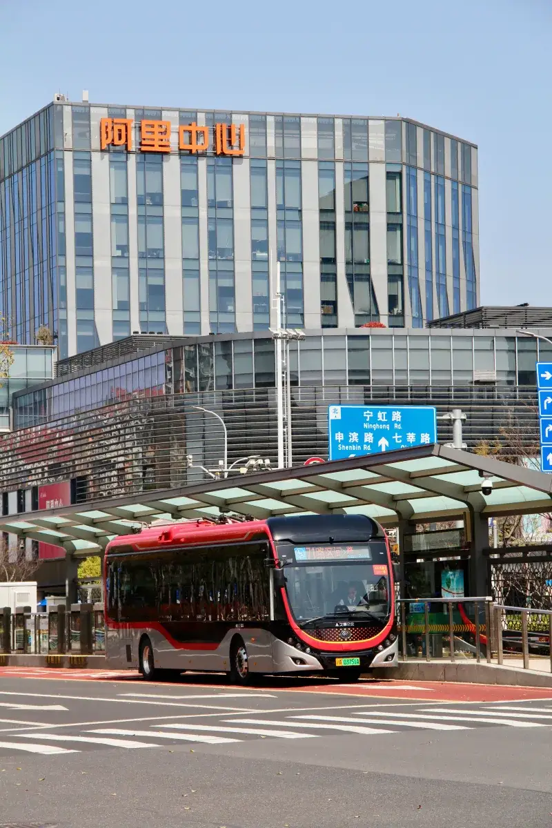 Electric bus in front of Alibaba building, capturing modern urban transit in Shanghai.