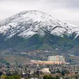 A winter aerial view of snow-capped mountains with San Bernardino cityscape in the foreground, California.