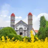 Exterior of historic Iglesia de San Rafael Catholic church in Costa Rica located in beautiful garden with green and yellow plants