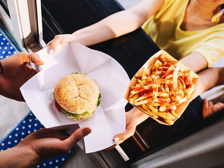 A food server hands a hamburger and some fries to a customer