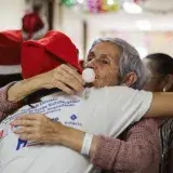 Elderly woman hugging in hospital during festive celebration, fostering connection and joy.
