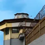 A prison watchtower with barbed wire against a clear blue sky in Bali, Indonesia.