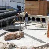 Workers at a construction site in Acapulco, Mexico, with stacked bricks and large pipes.