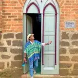 A man in a colorful poncho stands at Monasterio Santa Clara entrance, looking upwards.