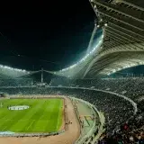 A crowded soccer stadium under bright lights at night, capturing the excitement of a live sports event.