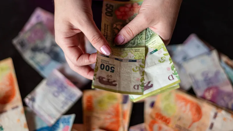 Closeup of hands counting Argentinian pesos in Buenos Aires, Argentina.