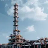Vertical shot of an oil refinery tower against a blue sky in Trzebinia, Poland.
