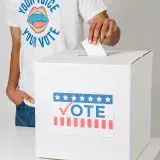 Close-up of a man casting a vote in an election, focusing on the ballot box.
