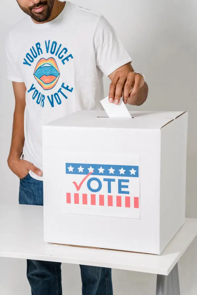 Close-up of a man casting a vote in an election, focusing on the ballot box.