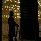 Silhouette of a soldier holding a rifle, displayed against a wall with historical inscriptions in Ankara, Türkiye.