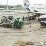 Ground support services in action at an airport terminal with visible aircraft and service vehicles.