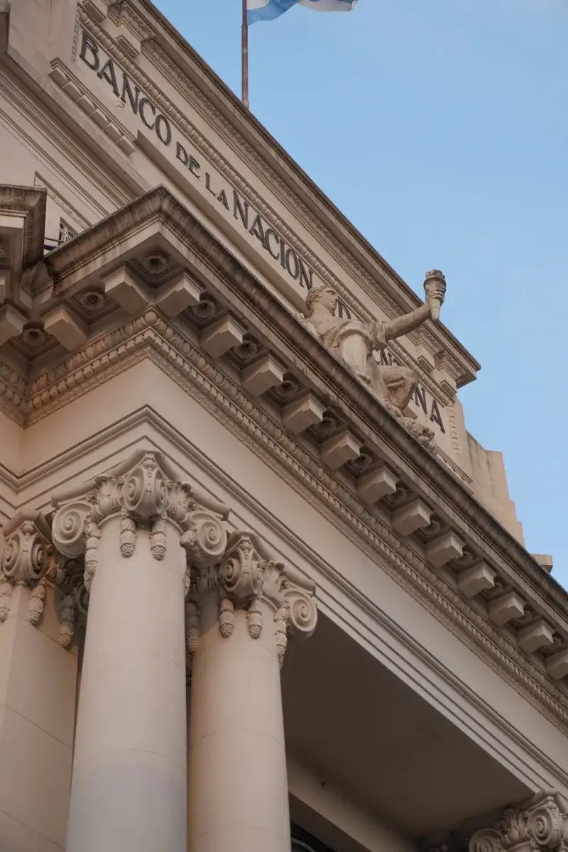 Neoclassical facade of Banco de la Nación Argentina featuring ornate columns and clear blue sky.