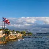 Unavista pintoresca del frente marítimo de Puerto Rico con una bandera ondeando contra el fondo del mar y el paisaje urbano.