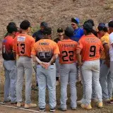Youth baseball team gathers in a huddle during a game for strategy discussion.