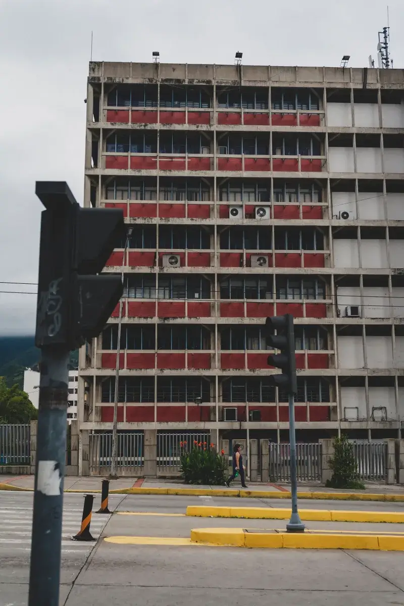 Street view of a high-rise building in Mérida, Venezuela with crosswalk and traffic light.