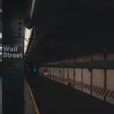 Moody view of Wall Street subway station in New York City, showcasing urban architecture.